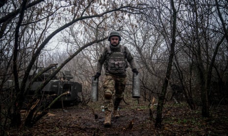 A Ukrainian artilleryman carries empty cartridge cases at a position along the Bakhmut frontline.