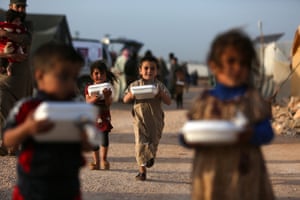 Displaced Syrian children return to their tents with boxes of food, before the iftar meal distributed by a local charity in Idlib province, Syria