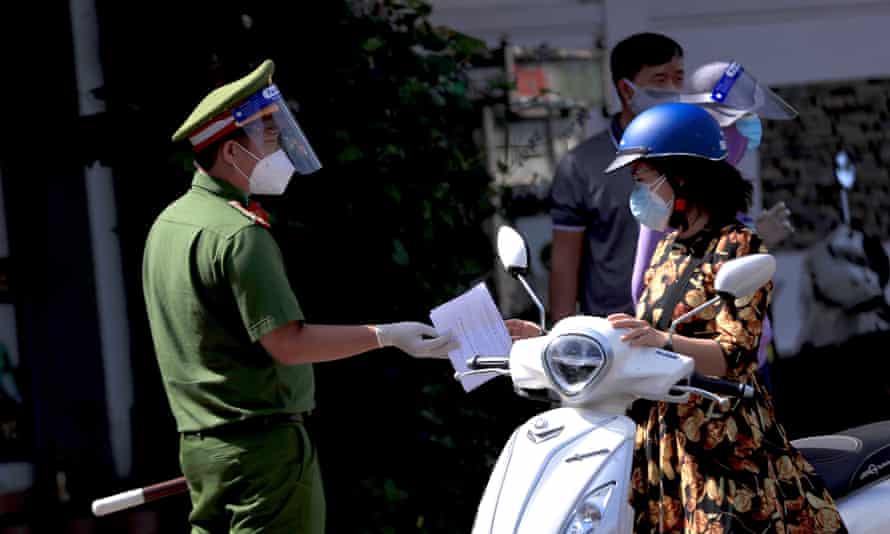 A policeman hands back a commuter’s travel permit at a checkpoint in Vung Tau