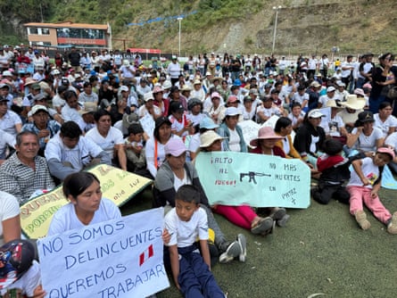 A group of men, women and children sit on a football pitch holding placards