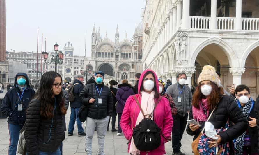 Tourists wearing protective masks visit Venice.