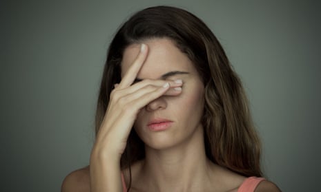 A woman with her hand over her eyes looking stressed.