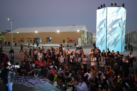 Activists listen to a demonstration at dusk at the summit.