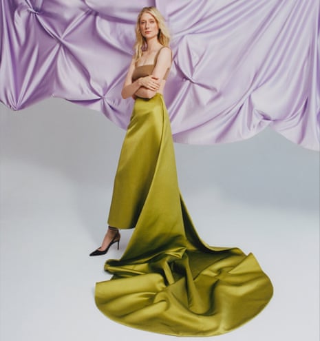 Actor Elizabeth Debicki in long green skirt, arms folded, in front of draped lilac fabric