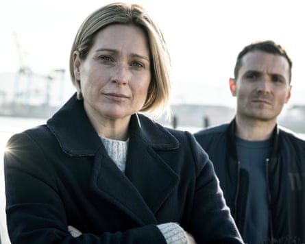 Grace in her white fisherman’s sweater and navy coat, with Stevie in the background.