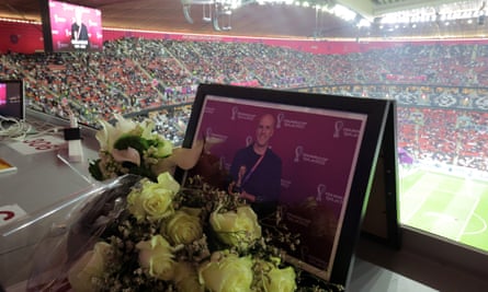 Flowers and a photograph are placed in the Al Bayt Stadium press box in tribute to Grant Wahl.