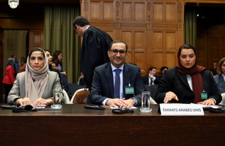 Two Arab women with loose hijabs and an Arab man sitting at a table in a court