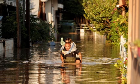 A firefighter carries a child through a flooded street in Larissa, Greece.
