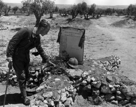 An officer of the International Brigades lays twigs on the mass grave of soldiers who died fighting in the civil war, circa 1937.