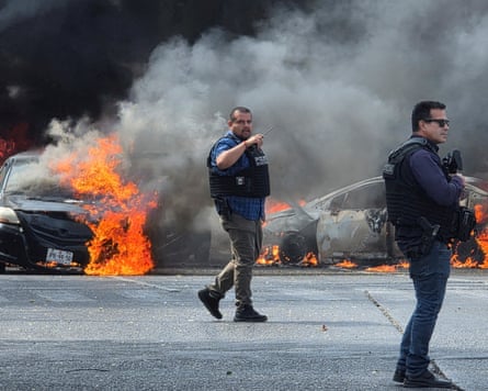 Two police officers next to cars set on fire