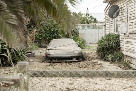A damaged car sits in dried mud.