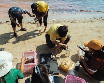 Seven people on a beach with boxes of scientific equipment and electronic devices