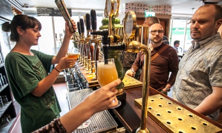 barmaid pouring craft beer as blokes wait