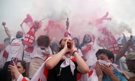 Georgia fans wave colourful scarves and set off smoke as they support their team