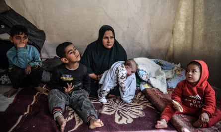 Zahra al-Ras sits in a tent with her children around her