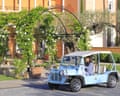 A driver of a tiny golf buggy style car in front of the entrance to the chateau