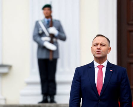 Man in military uniform forms part of welcoming ceremony for politician.
