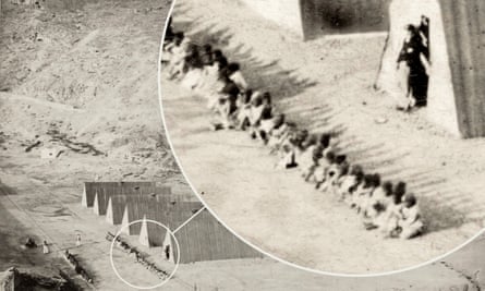 Enslaved people sitting in a line in front of accommodation huts in Rupert’s Valley in 1850.