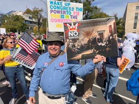 man at protest holds up sign saying ‘no kings’ with a historical painting of the US founding fathers