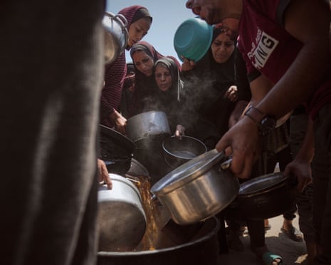 Displaced Palestinians receive donated food at a community kitchen in Gaza City, northern Gaza Strip on Tuesday, July 22, 2025.