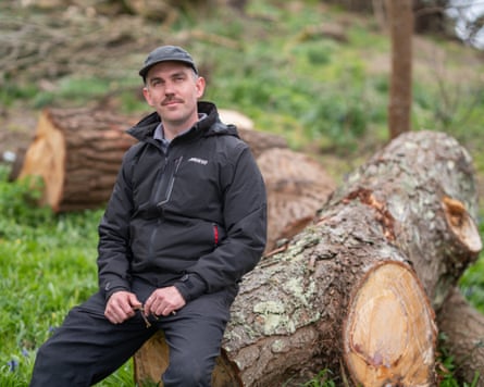 Jack Beesley sitting on a felled tree trunk or limb.