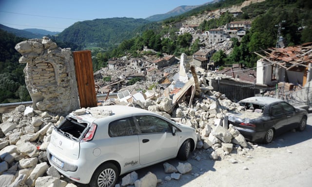 Cars sit amid the rubble from earthquake-damaged buildings in the central Italian village of Pescara del Tronto.
