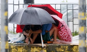 Manila residents huddle under their umbrellas as Typhoon Koppu hits.