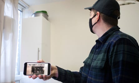 Mansfield Court resident Max, in a baseball cap and face mask, holds his phone to show a picture of the mould previously in his kitchen
