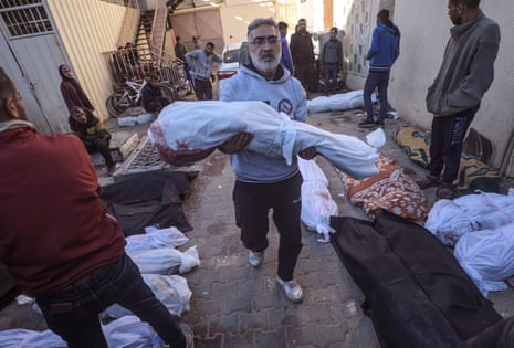 A Palestinian carries the body of a child after an Israeli airstrike in Nusairat refugee camp, at Al Aqsa hospital in Deir Al Balah, 20 March.