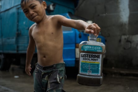 A boy plays with an old Listerine plastic bottle.