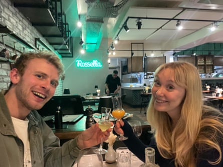 A man and a woman clinking glasses in a restaurant.