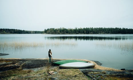 Canoeist stands lakeside in Dalsland, West Sweden, from where you can canoe across the lake to uninhabited Björken island.
