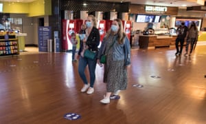 Les clients masqués adhèrent à la distance sociale lorsqu'ils se rendent au cinéma pour la première fois depuis le début du verrouillage.