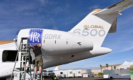 Workers apply a Rolls Royce decal to the engine of a Bombardier Global 6500 business jet