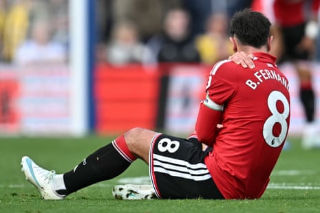 Bruno Fernandes sits on the pitch holding his shoulder after an injury