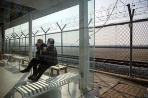 An elderly couple drink coffee in front of a barbed wire fence at the Imjingak tourist park in Paju, South Korea