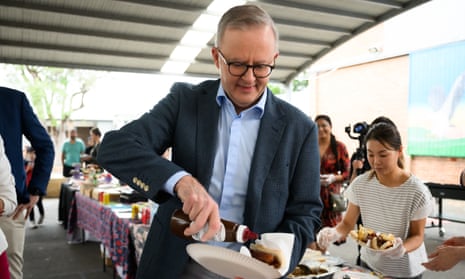 Prime Minister Anthony Albanese applies BBQ sauce to a sausage.