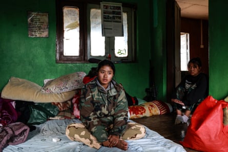 Anina sitting on a bed. Another girl stands in the doorway.