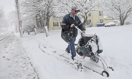 A mailman uses a cart to deliver mail in the snow in Fairhaven, Massachusetts.