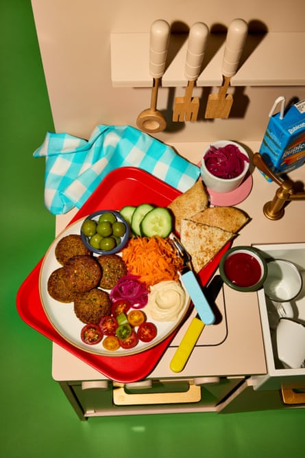 Child's play kitchen with utensils hanging up and food on a plate