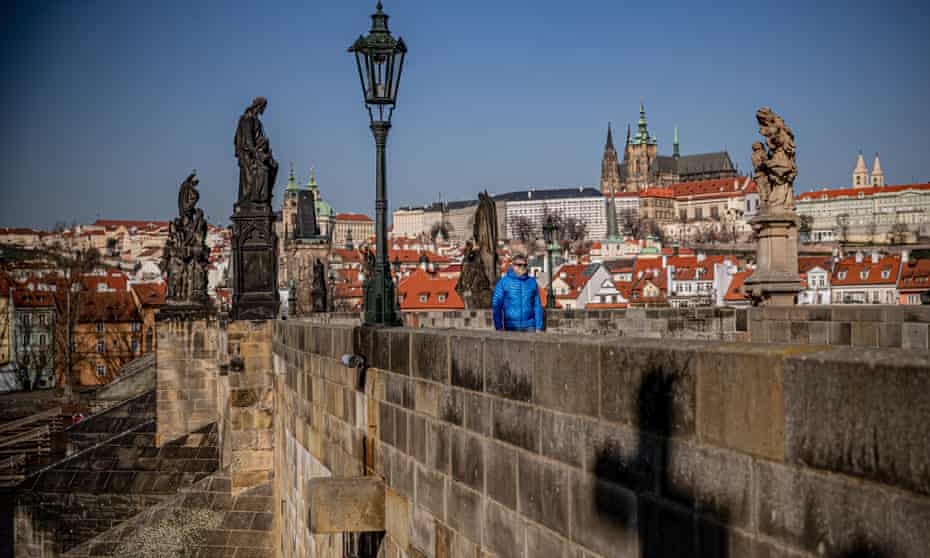 A man wearing a protective face mask walks on Charles Bridge in Prague