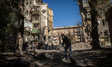 A mans clears debris in front of an area in Zaporizhzhia that had been hit by an airstrike.
