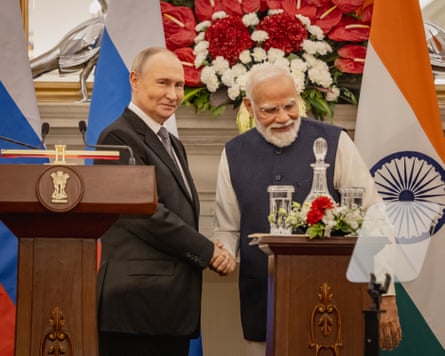 Vladimir Putin and Narendra Modi smile after speaking from podiums; their national flags are behind them