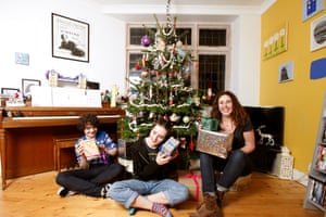 Ellison, Lola and Gilly each holding a present and smiling, sitting on the floor in front of their tree with popcorn garlands