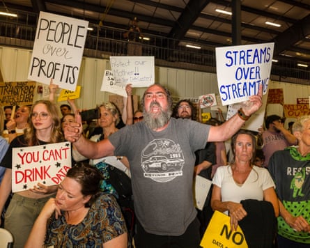 A crowd of people with signs including 'People over profits'