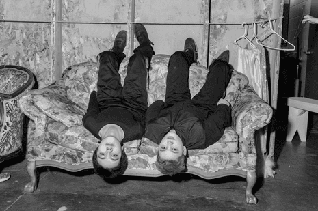 Young men sitting upside down on a chintzy sofa