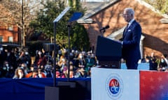 a man in a blue suit speaks from behind a lectern