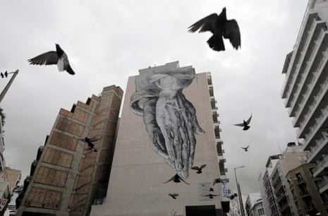 Pigeons fly over a building covered with graffiti in central Athens, Greece, 24 February 2015.