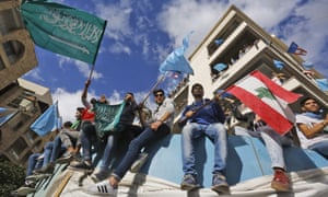 Supporters of Saad Hariri wave the Lebanese flag alongside the Saudi and Future Movement flags as they gather at his home in Beirut on Wednesday