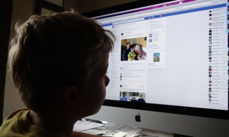 Stock picture of a boy looking at a Facebook page on a computer